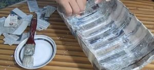 Couvrez deux fois le blanc de la boîte en plastique avec des bandes de papier journal des deux côtés.