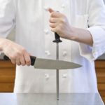 Un cuisinier aiguise un couteau avec du musat.